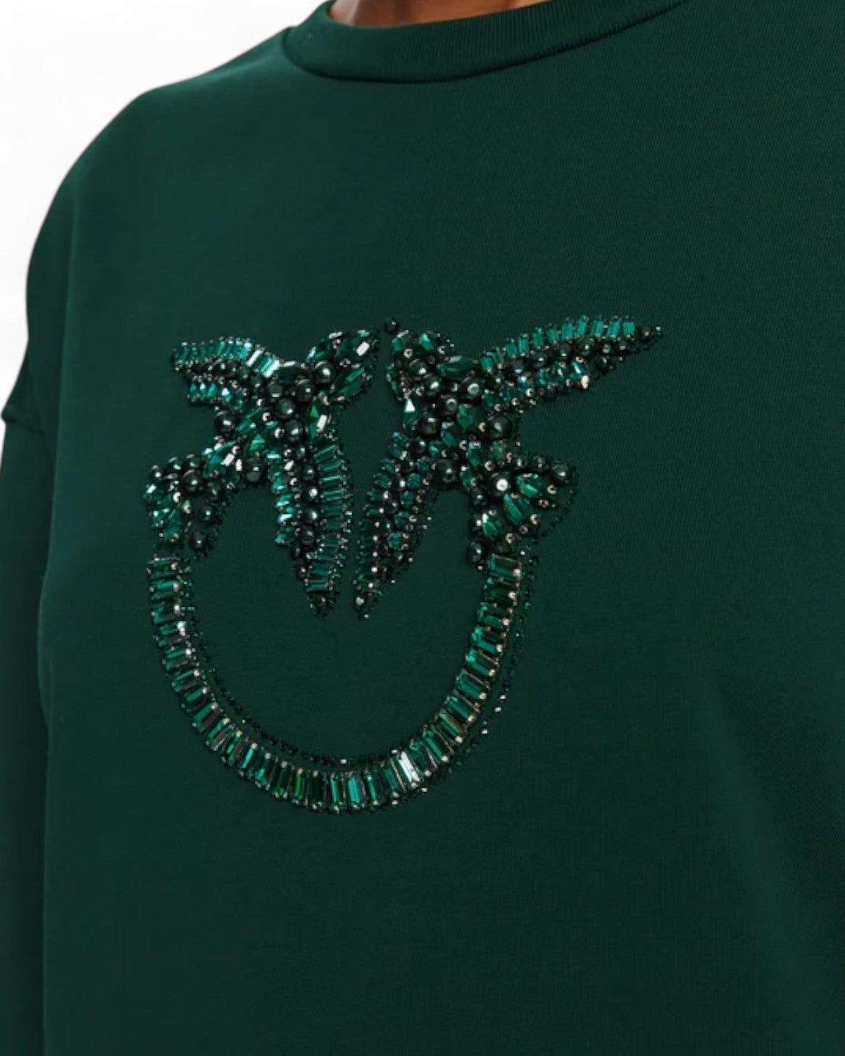 Primo piano del ricamo gioiello Love Birds su felpa PINKO, con perle e cristalli verdi che creano un motivo elegante e luminoso.